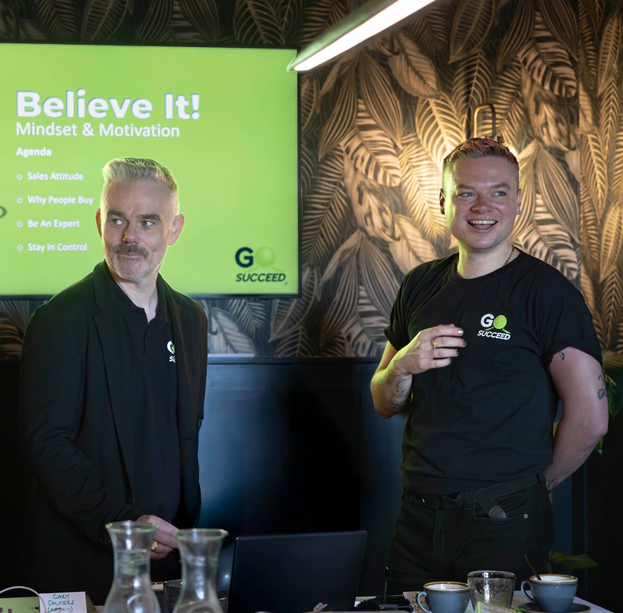 GoSucceed founders Gary Salters and Jonny Monroe stand in front of room of clients presenting